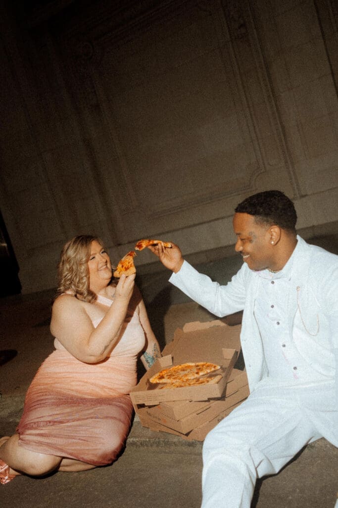 Couple sharing pizza during a downtown Mobile engagement session photographed by Mobile Alabama wedding and engagement photographer Highland Film + Photo.