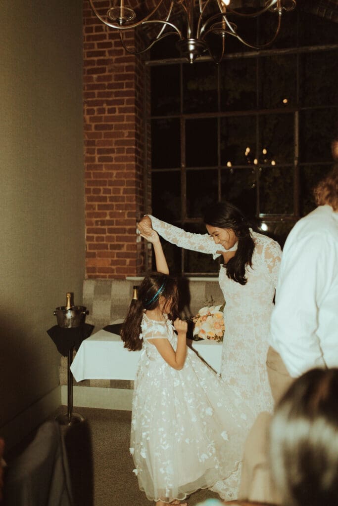 Bride twirls with her flower girl during a lively wedding reception in Chattanooga, Tennessee, photographed in a candid, documentary style that captures genuine connection and joy.