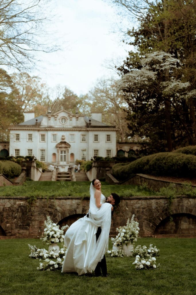 Bride and groom sharing a joyful moment in front of the Swan House in Atlanta, Georgia during their wedding portraits.