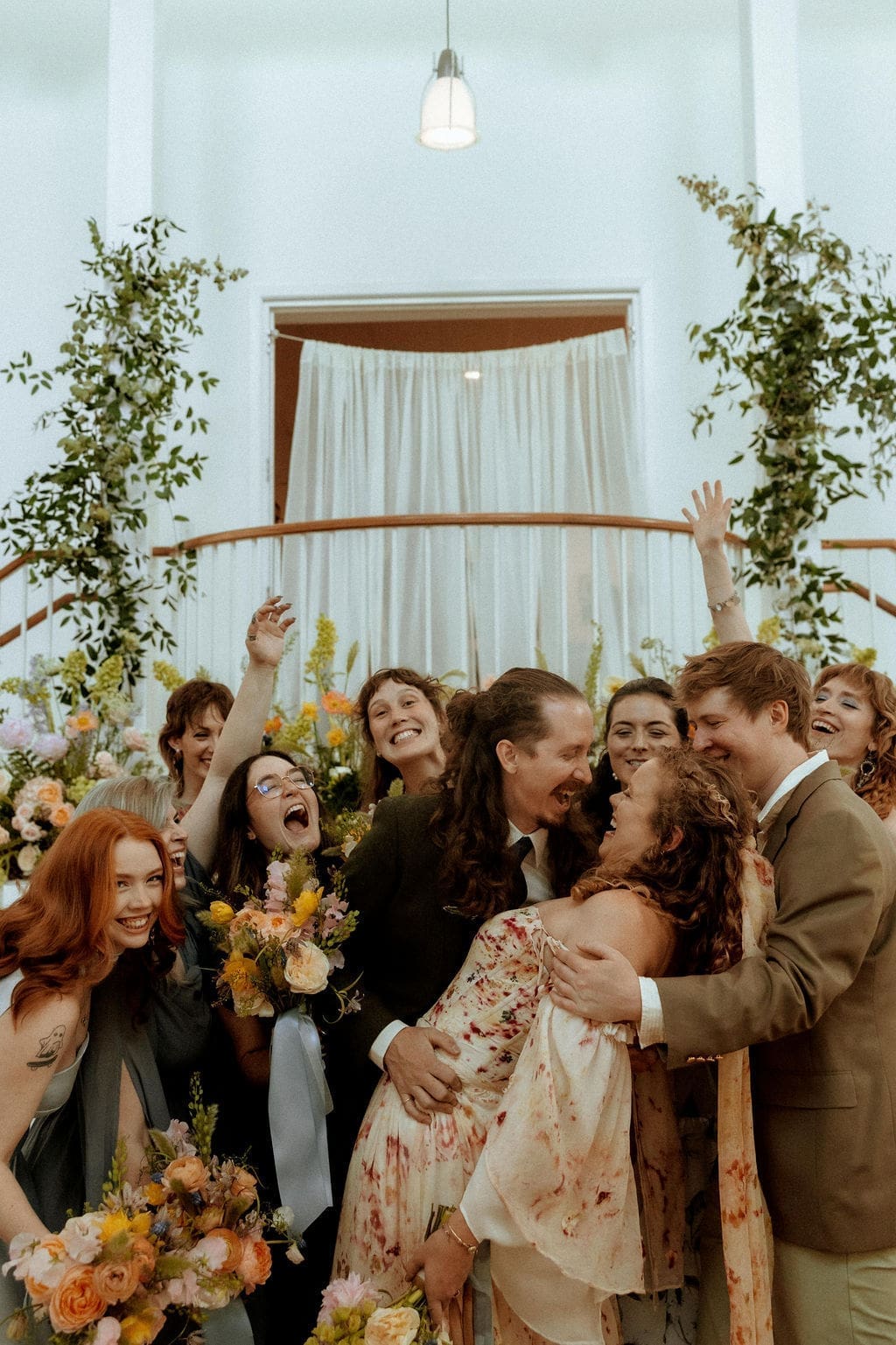 Bride and groom celebrating with their wedding party inside the Eastern Shore Art Center during their colorful spring wedding in Fairhope, Alabama.
