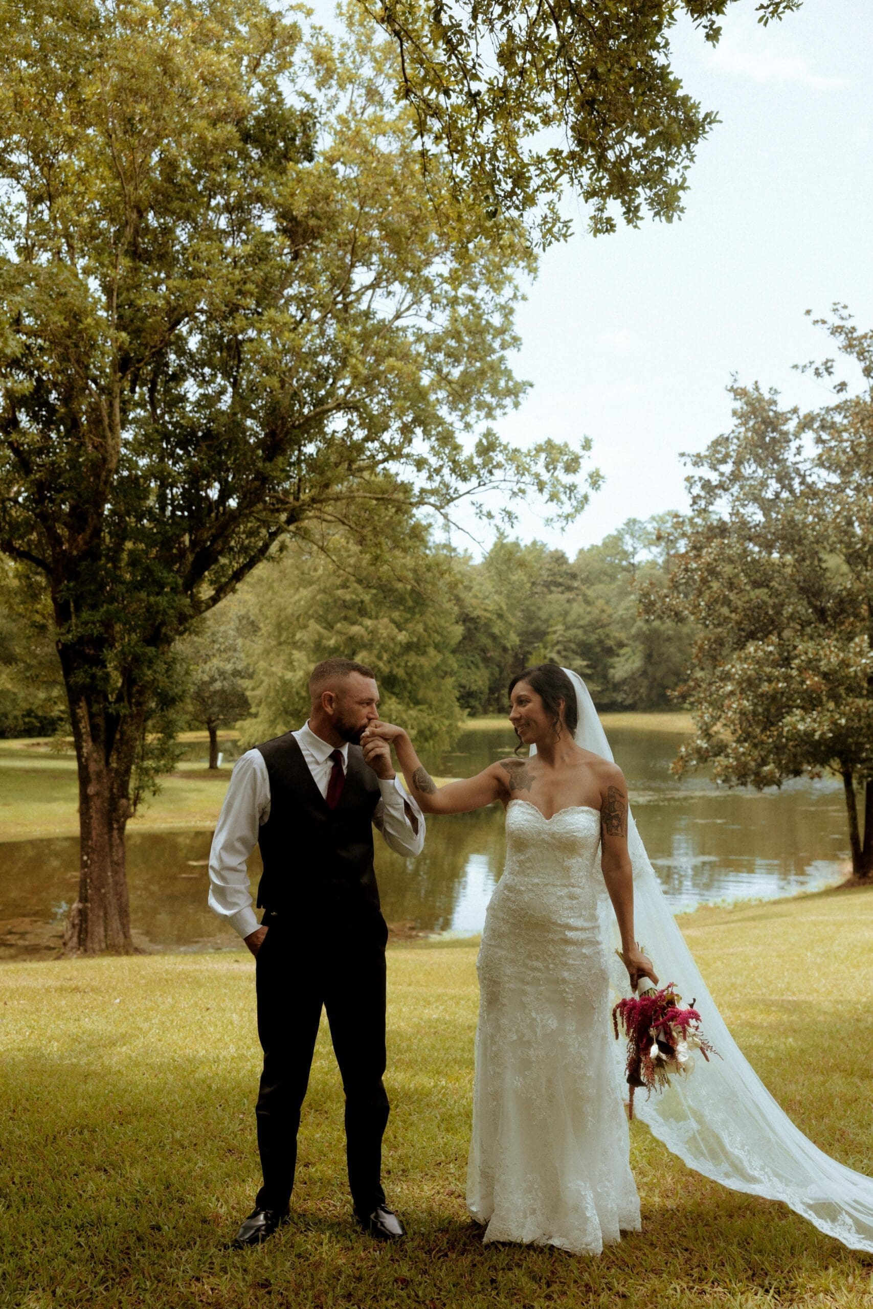 Bride and groom sharing a joyful moment beside the lake during their wedding at Spring Lake Estate in Mobile, Alabama.