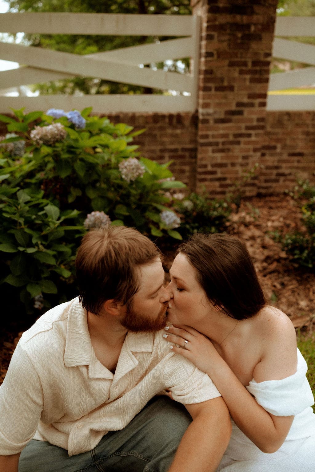 Couple sharing a kiss during a summer engagement session in Mobile, Alabama at golden hour.